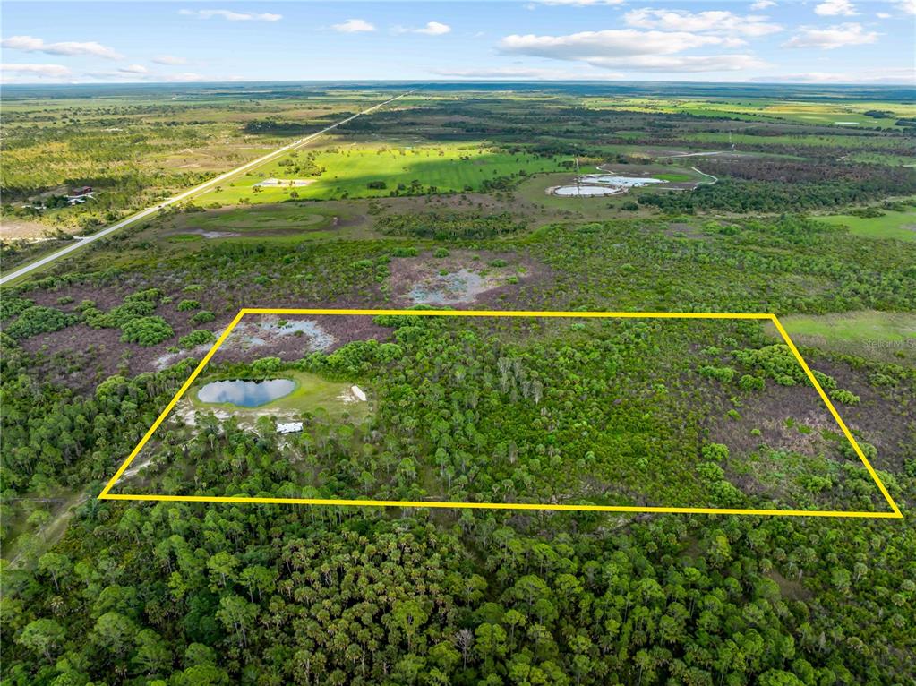 An aerial view shows a rectangular plot of land containing a pond and dense vegetation — 49909 BERMONT ROAD, PUNTA GORDA, FL