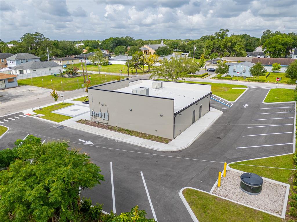 An aerial view shows a commercial building with a flat roof and surrounding asphalt parking lot — 215 CENTER STREET UNIT 227, WINTER GARDEN, FL