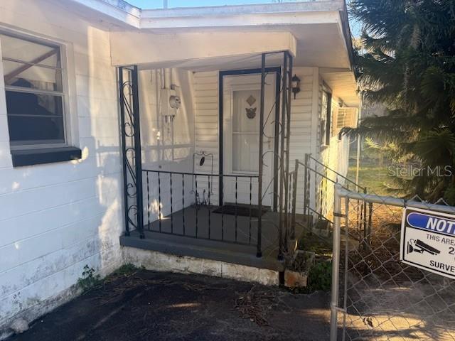 An exterior view of a house entrance with a small porch and wrought iron railing — 1813 DANIELS STREET, KISSIMMEE, FL