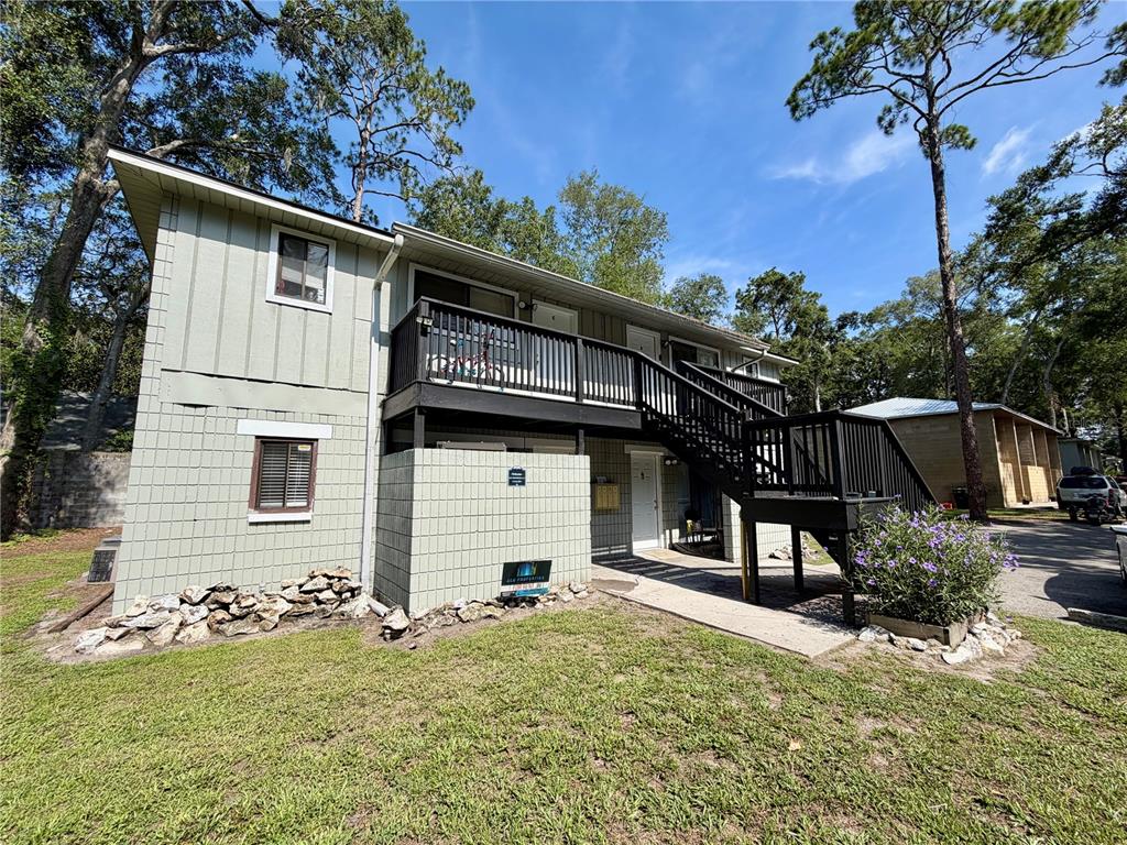 A two-story apartment building with light green siding, a black wooden staircase, and a balcony — 712 SW 70TH TERRACE, GAINESVILLE, FL