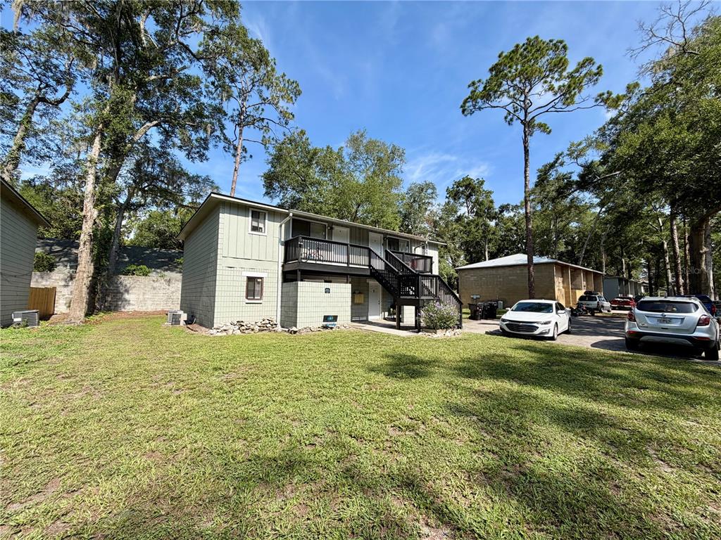 A two-story apartment building with light green siding and an exterior wooden staircase — 712 SW 70TH TERRACE, GAINESVILLE, FL