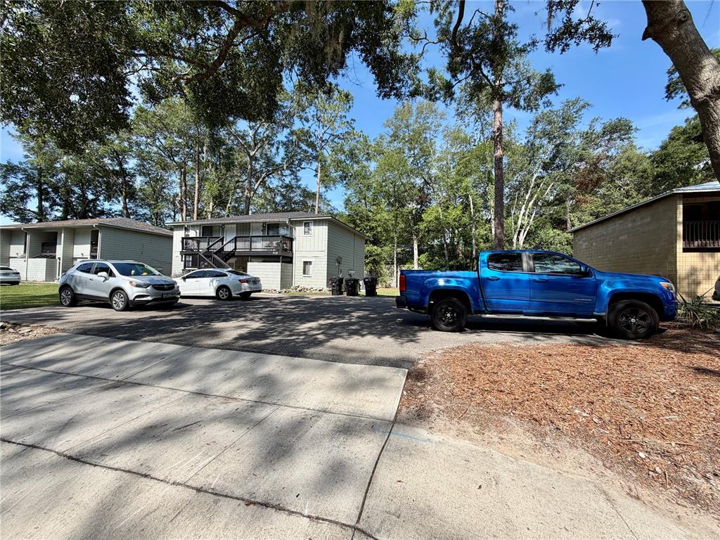 A paved parking area sits in front of a two-story apartment building with parked vehicles — 712 SW 70TH TERRACE, GAINESVILLE, FL