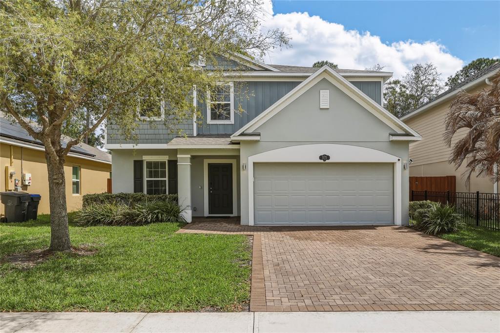A two-story house with a gray garage, blue siding, and a brick paver driveway — 5573 REAGAN AVENUE, TITUSVILLE, FL