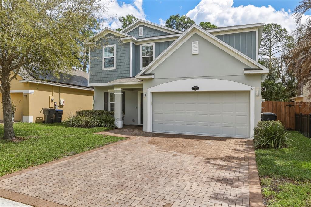 A two-story house with a paver driveway, a two-car garage, and blue-gray siding — 5573 REAGAN AVENUE, TITUSVILLE, FL