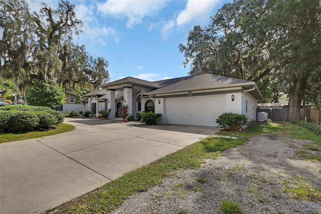 A single-story house with a white garage, concrete driveway, and large oak trees — 2465 ROYAL ROAD, DELAND, FL