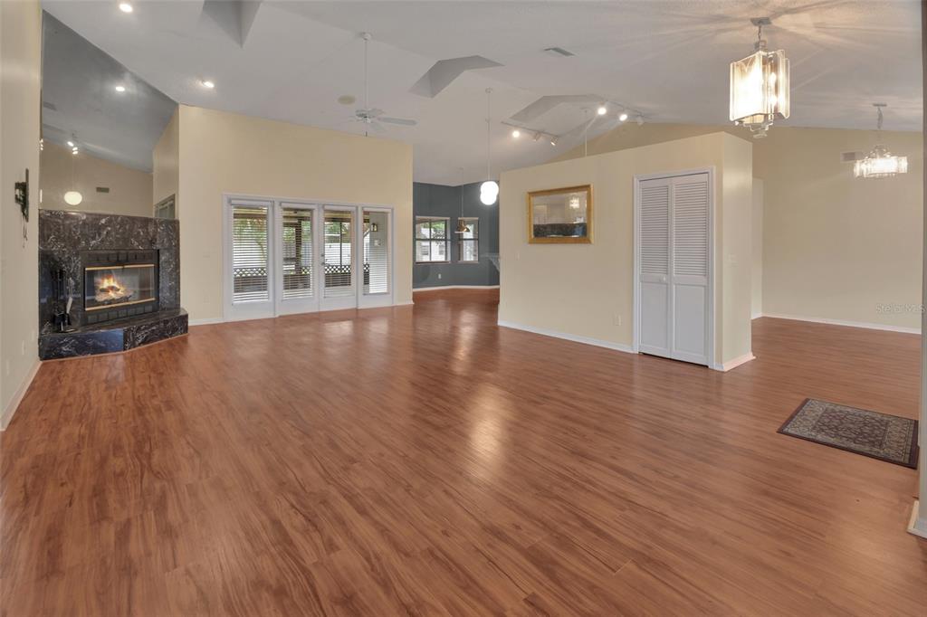 A spacious living room features wood-look flooring, a corner fireplace, and vaulted ceilings — 2465 ROYAL ROAD, DELAND, FL