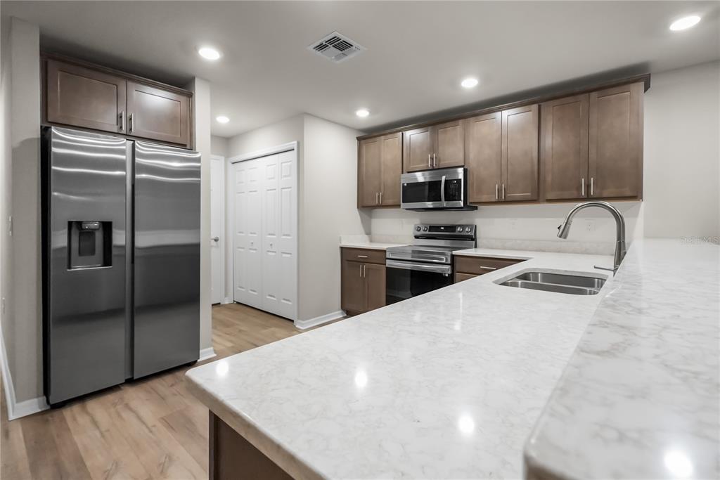 A modern kitchen features stainless steel appliances, brown cabinets, and a white marble-patterned countertop — 2726 IDYLL LAKES CIRCLE, PLANT CITY, FL