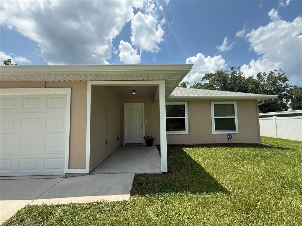 A tan single-story house features a white garage door, a covered entryway, and two windows — 350 W COURT STREET UNIT A, BUNNELL, FL
