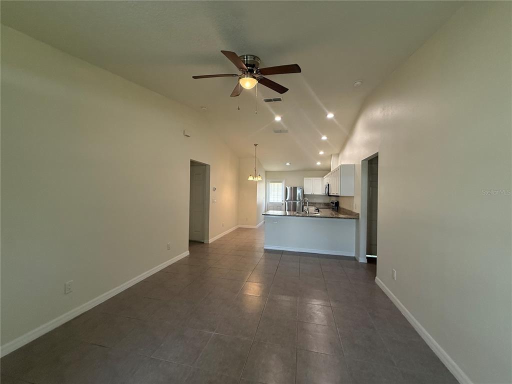 An open-concept living and kitchen area features tile flooring, white cabinetry, and a ceiling fan — 350 W COURT STREET UNIT A, BUNNELL, FL