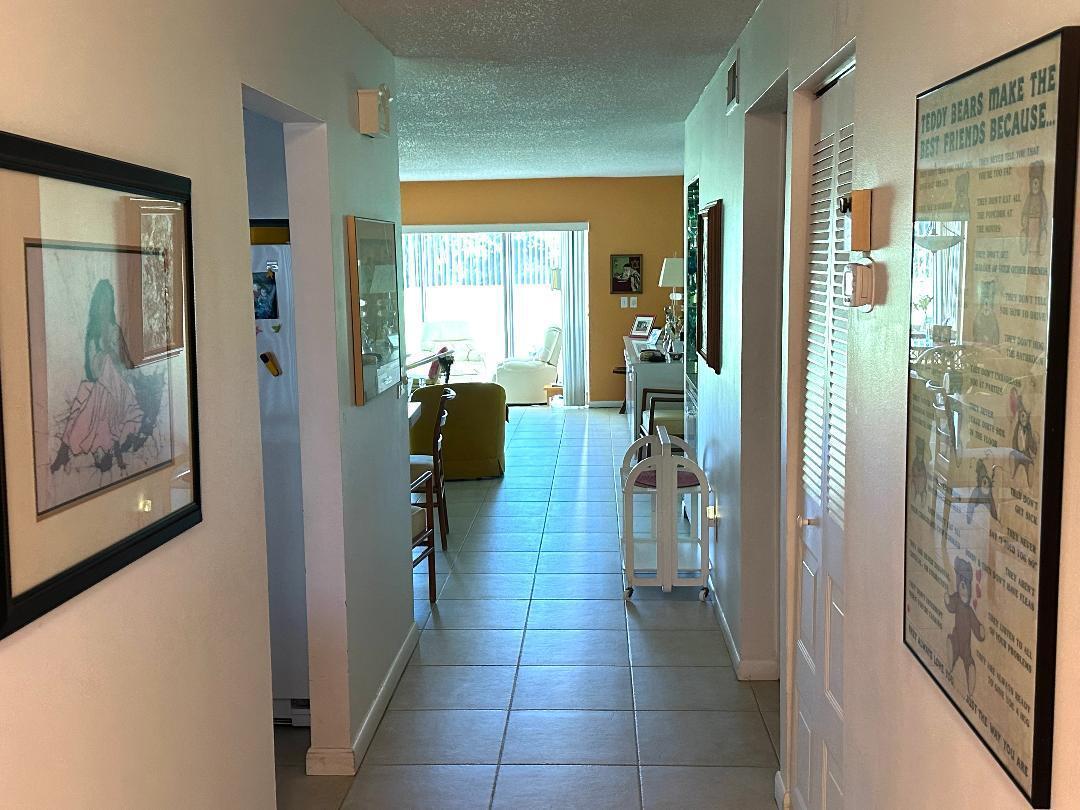 A tiled hallway leads from the foreground into a living room with sliding glass doors — 8305 Casa Del Lago, Boca Raton FL 33433, BOCA RATON, FL