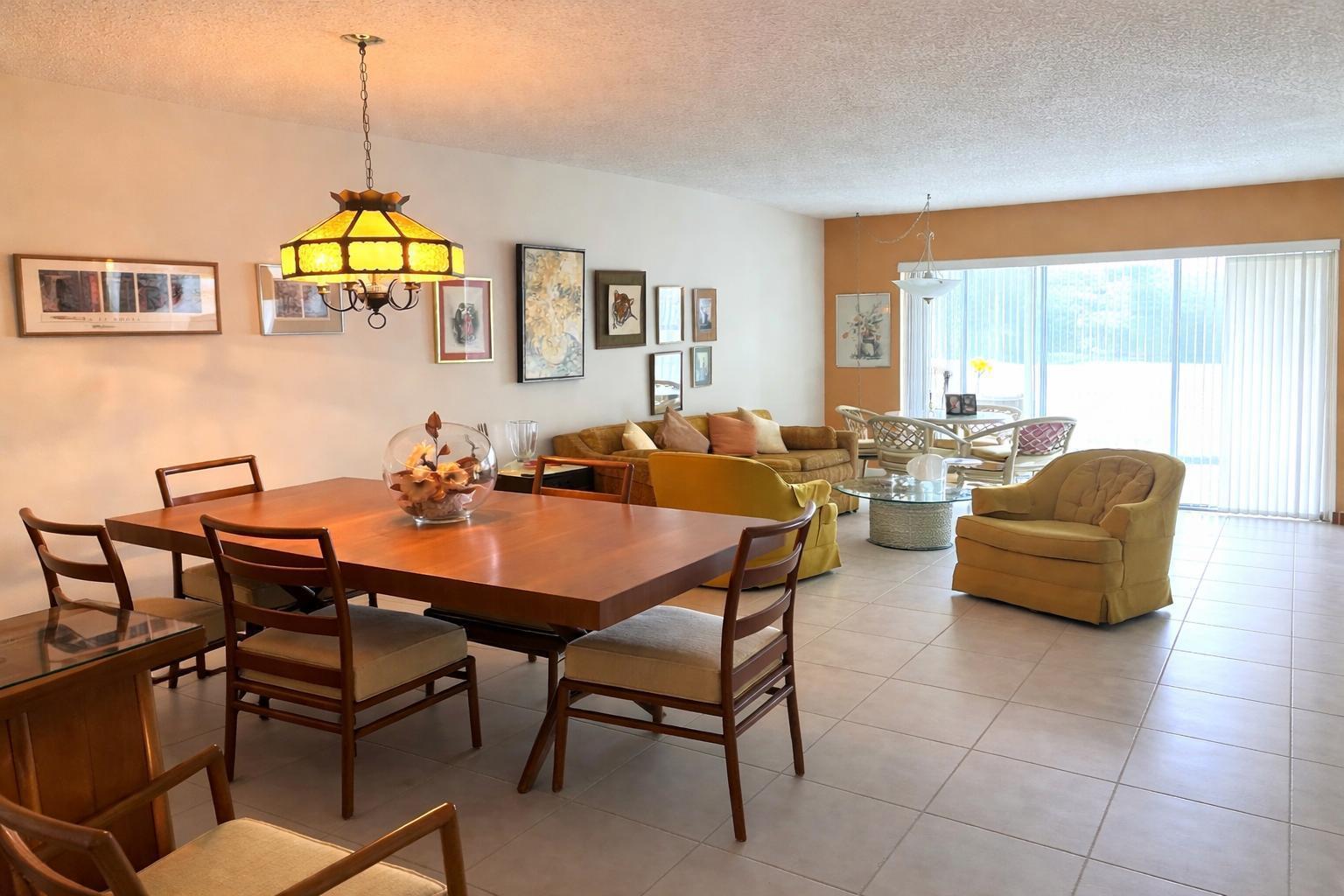 A dining area and living room with tile floors, yellow furniture, and large sliding glass doors — 8305 Casa Del Lago, Boca Raton FL 33433, BOCA RATON, FL