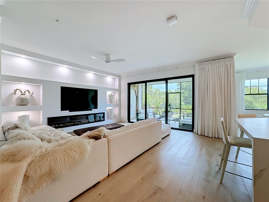 A living room features a large sectional sofa, a fireplace, built-in shelving, and sliding doors — 10051 CROOKED CREEK DRIVE UNIT 102, VENICE, FL