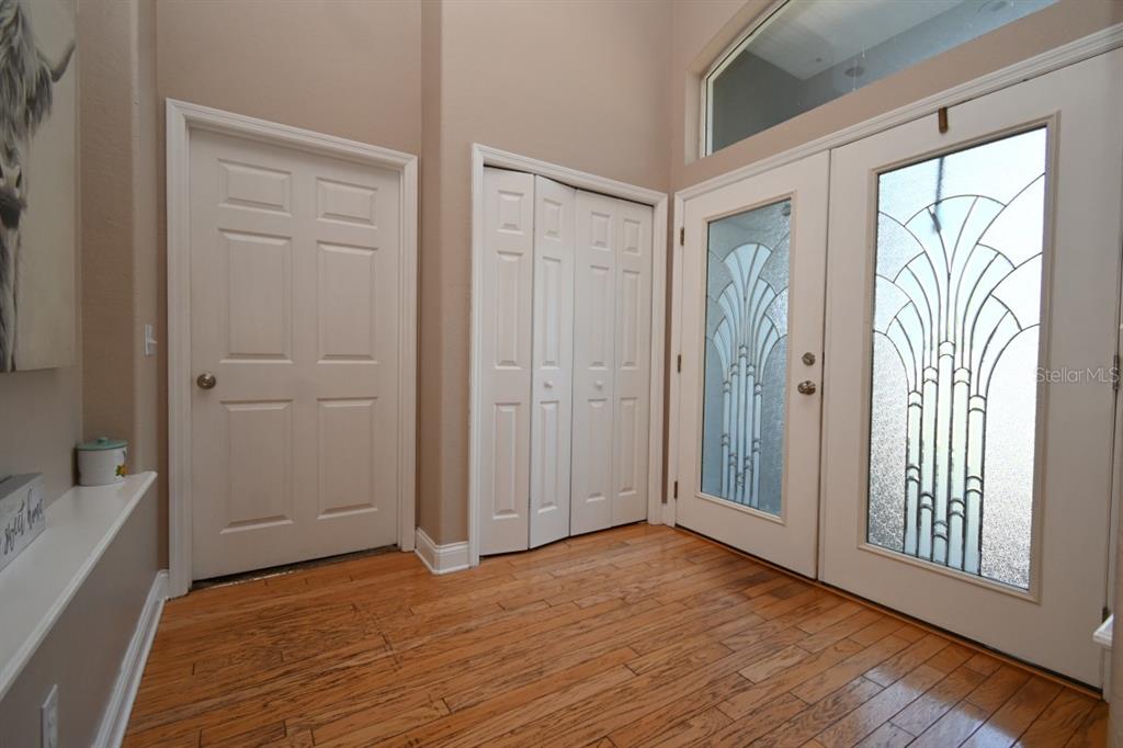 An entryway features hardwood floors, a closet with bifold doors, and double front doors with glass — 12106 PALM STREET, SAN ANTONIO, FL