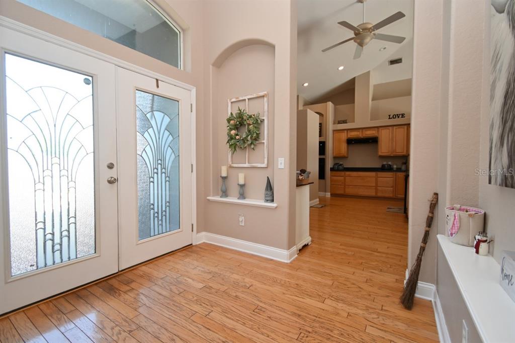 An entryway with hardwood floors, a decorative wall niche, and double glass-paneled front doors — 12106 PALM STREET, SAN ANTONIO, FL