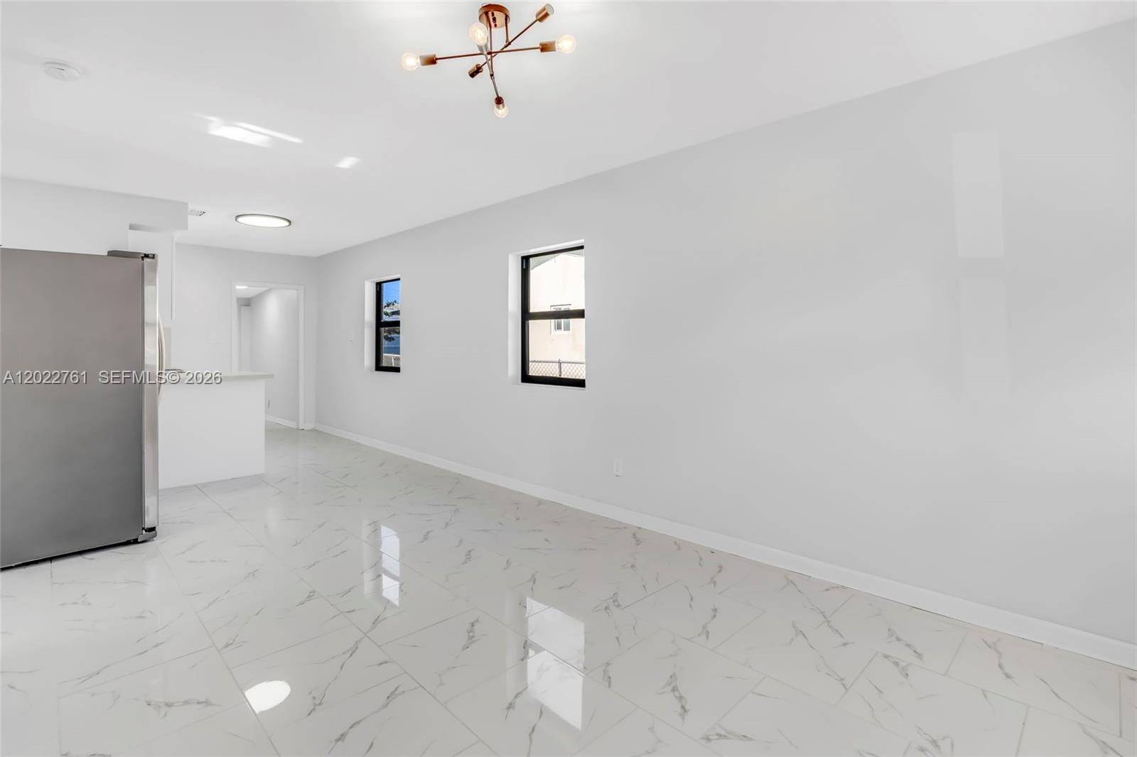 A bright room features white marble-look tile flooring, two windows, and a modern light fixture — 6312 SW 19th St # 1, Miramar FL 33023, MIRAMAR, FL