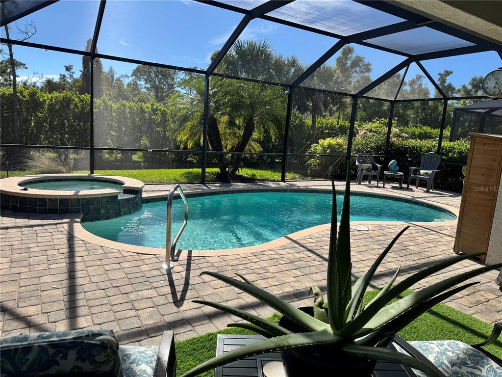 A screened-in pool area features a spa, paver patio, and outdoor seating — 9481 RUSCELLO COURT, FORT MYERS, FL