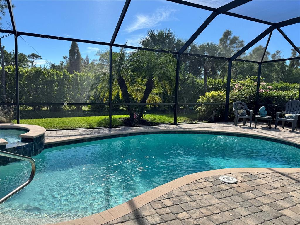 A screened-in pool area features a spa, paver patio, and lush tropical landscaping — 9481 RUSCELLO COURT, FORT MYERS, FL