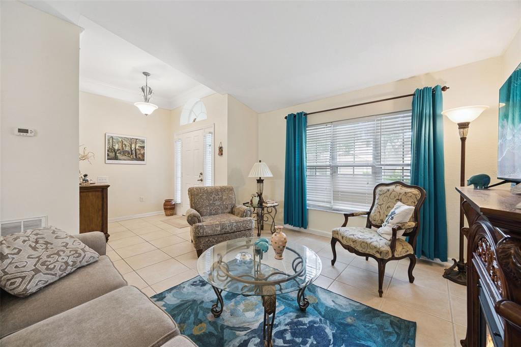 A living room with tile floors, a glass coffee table, and a blue area rug — 6169 FROGGATT STREET, ORLANDO, FL