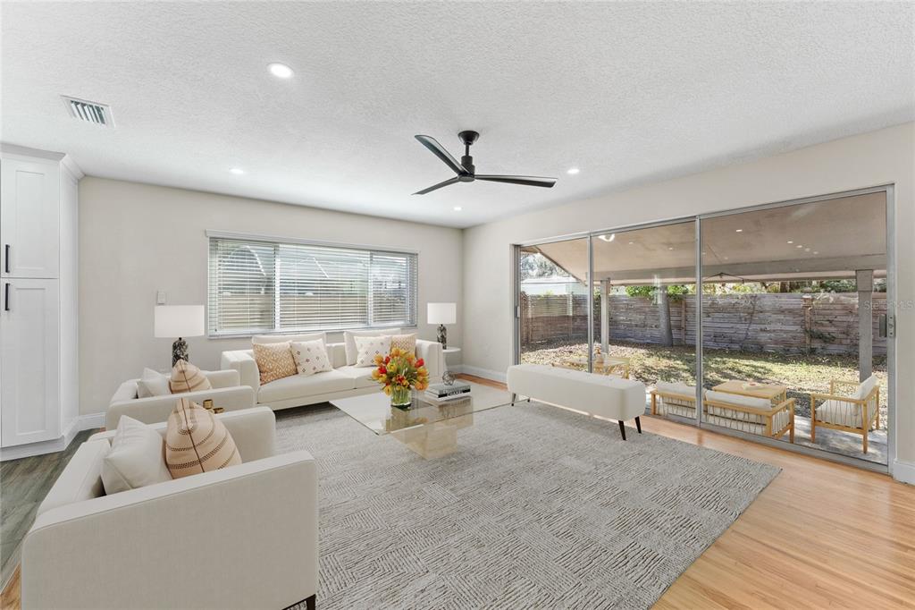 A living room features white furniture, a glass coffee table, and large sliding glass doors — 5106 SAINT MICHAEL AVENUE, BELLE ISLE, FL