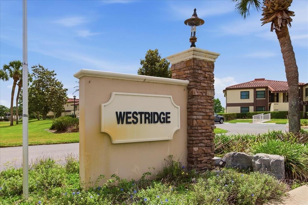 A stone and stucco monument sign for Westridge stands near a road and palm trees — 6111 LAKE POINTE DRIVE UNIT 202, ORLANDO, FL