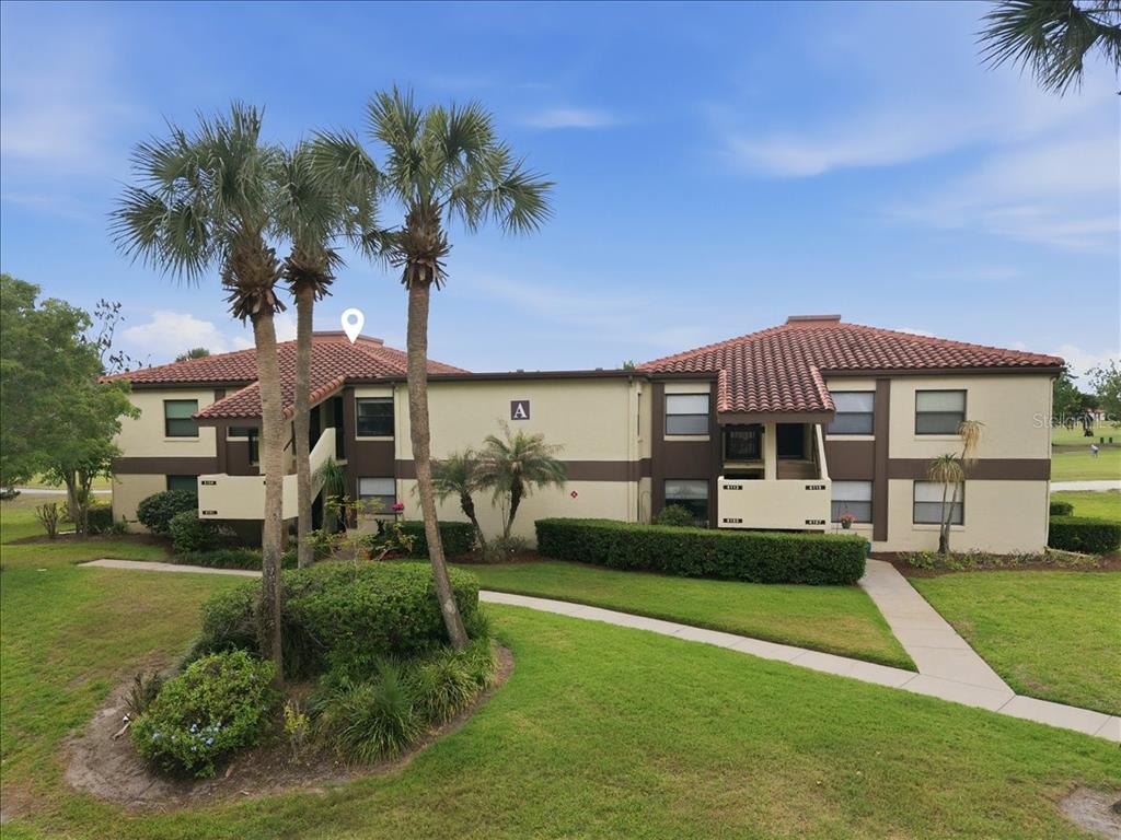 A two-story apartment building with a tile roof, beige stucco walls, and palm trees — 6111 LAKE POINTE DRIVE UNIT 202, ORLANDO, FL