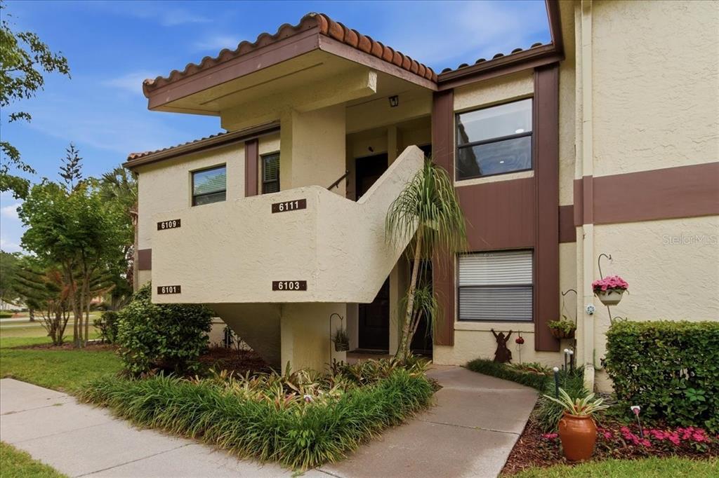 A two-story apartment building exterior features a concrete staircase leading to upper-level units — 6111 LAKE POINTE DRIVE UNIT 202, ORLANDO, FL