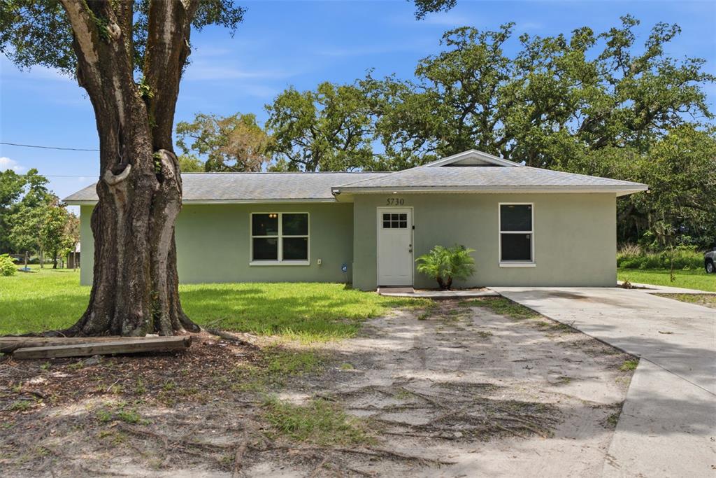 A single-story house with light green stucco siding and a concrete driveway — 5730 ANNA DRIVE, TAMPA, FL