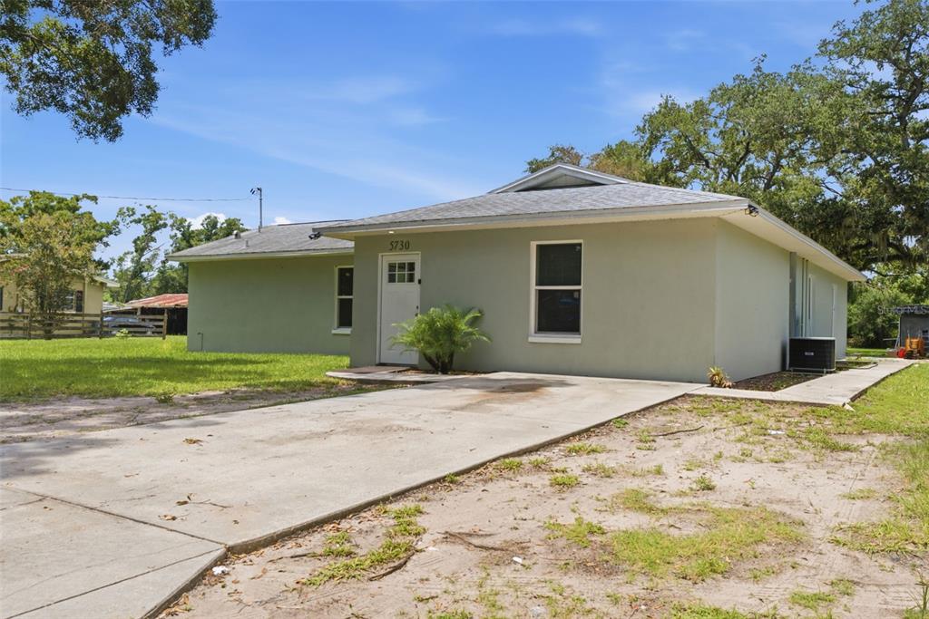 A single-story house with a light green exterior, a concrete driveway, and a hip roof — 5730 ANNA DRIVE, TAMPA, FL
