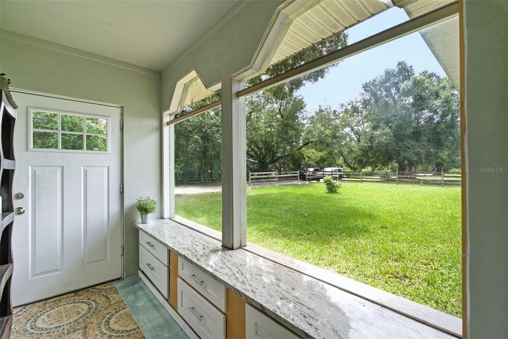 A sunroom features white cabinets with granite countertops, a patterned rug, and large windows — 5730 ANNA DRIVE, TAMPA, FL