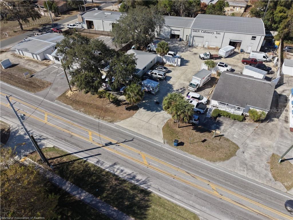 An aerial view shows a commercial property with multiple buildings, a parking lot, and vehicles — 2914 KENILWORTH BOULEVARD, SEBRING, FL