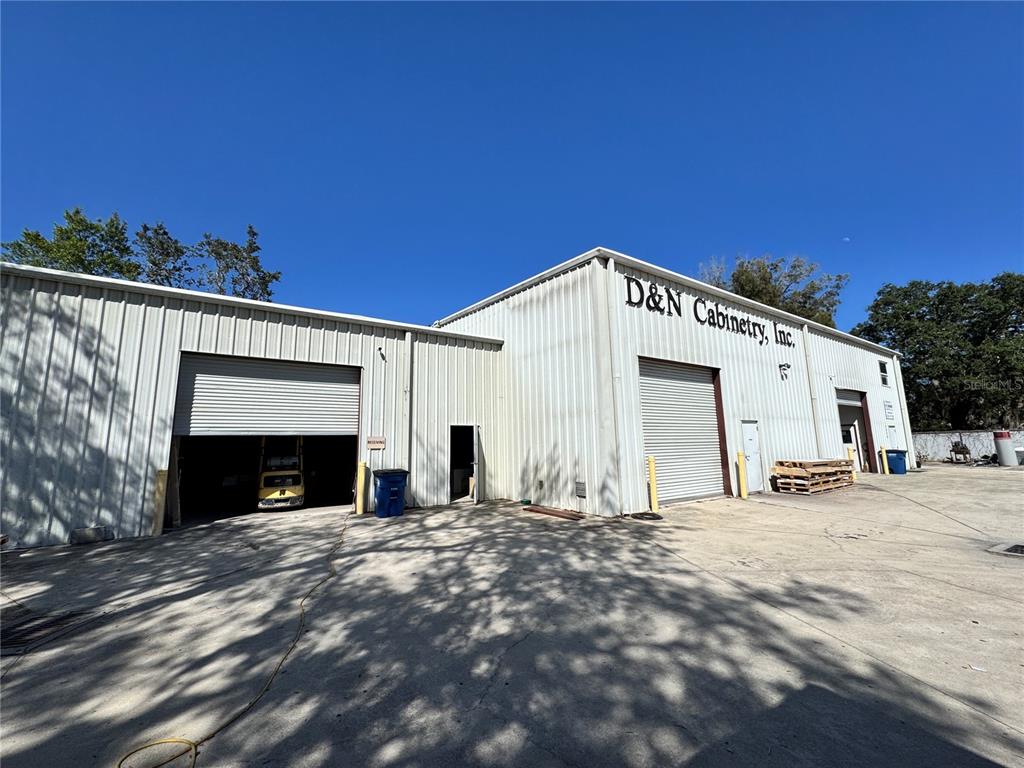The exterior of a white metal industrial building features two large roll-up garage doors — 2914 KENILWORTH BOULEVARD, SEBRING, FL