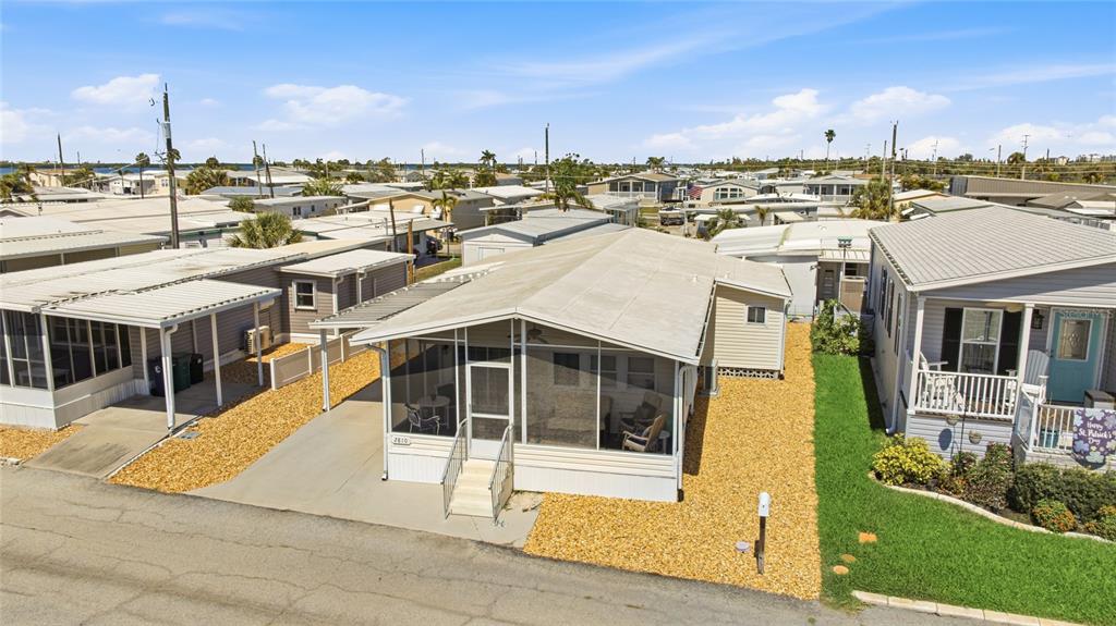 An exterior view of a manufactured home with a screened-in front porch and gravel landscaping — 2810 14TH STREET W, PALMETTO, FL