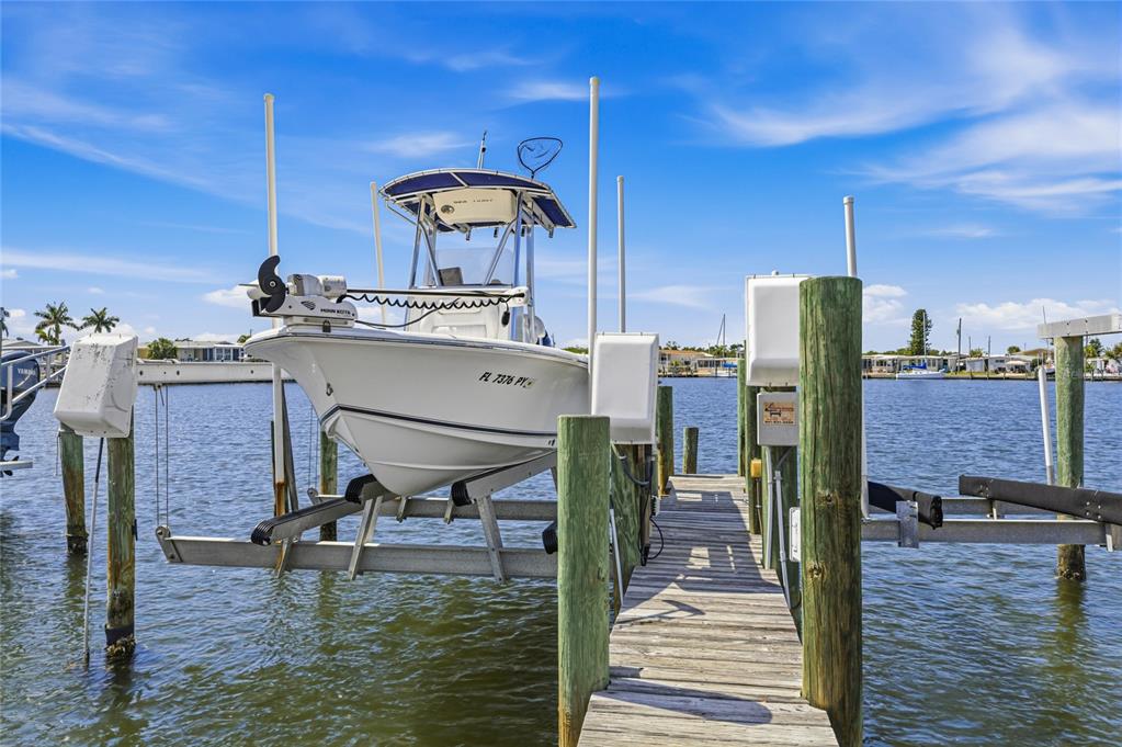 A white motorboat sits on a boat lift at the end of a wooden dock — 2810 14TH STREET W, PALMETTO, FL