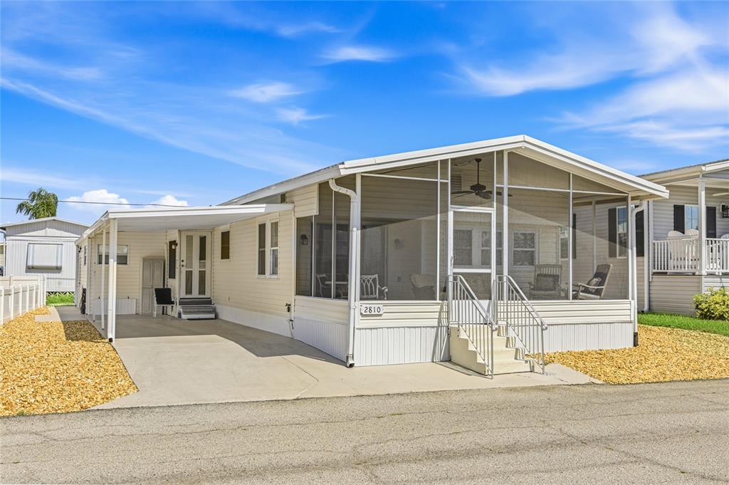 A single-story manufactured home with a screened-in porch, carport, and light-colored siding — 2810 14TH STREET W, PALMETTO, FL