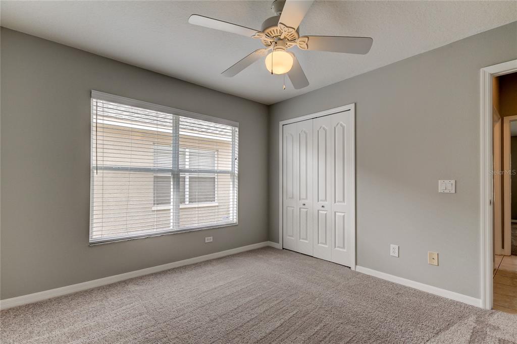 An empty bedroom features gray walls, carpeted flooring, a ceiling fan, and a white closet — 18829 MAISONS DRIVE, LUTZ, FL