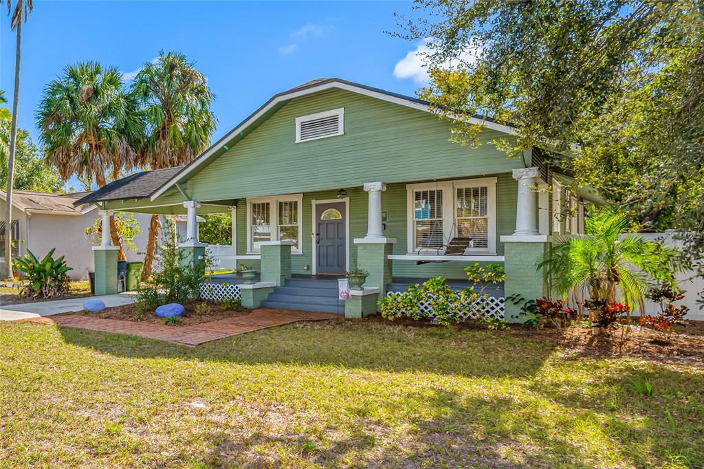 A green bungalow with a front porch, white columns, and a brick walkway — 304 W HENRY AVENUE, TAMPA, FL