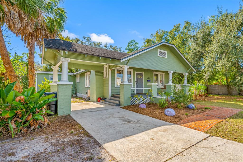 A green bungalow house features a front porch, a carport, and a brick walkway — 304 W HENRY AVENUE, TAMPA, FL
