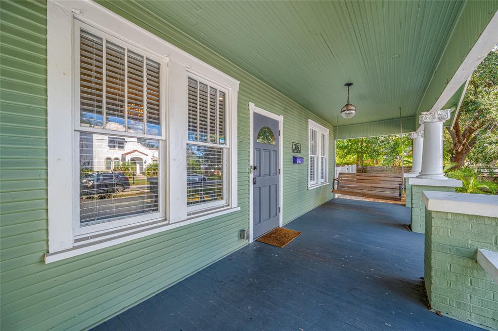 A covered front porch with green siding, a wooden swing, and a gray front door — 304 W HENRY AVENUE, TAMPA, FL