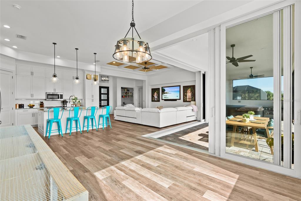 An open-concept kitchen and living area features wood-look flooring, a large island, and sliding doors — 16768 SAN EDMUNDO ROAD, PUNTA GORDA, FL