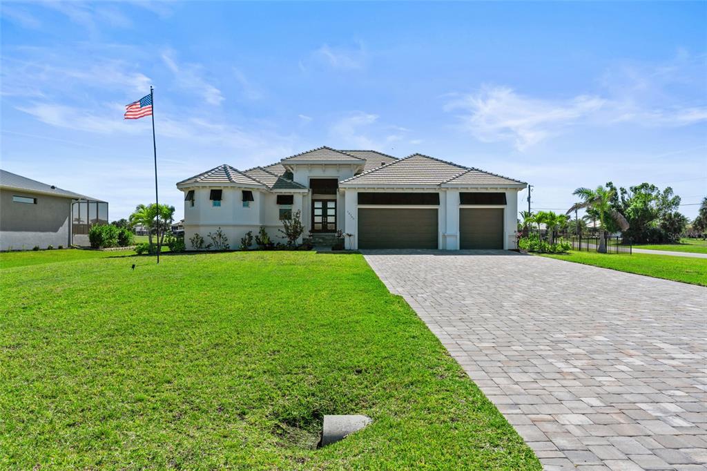 A single-story house with a paved driveway, a three-car garage, and an American flag — 16768 SAN EDMUNDO ROAD, PUNTA GORDA, FL