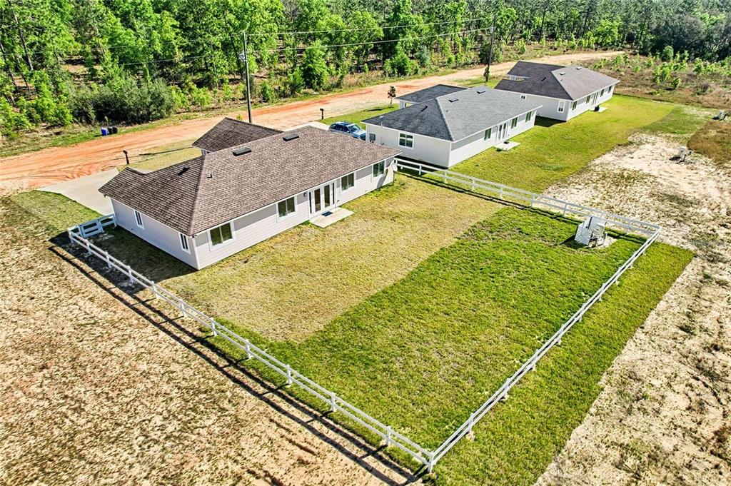 An aerial view shows three suburban houses with fenced backyards in a rural setting — 135 HARTFORD STREET, HAWTHORNE, FL