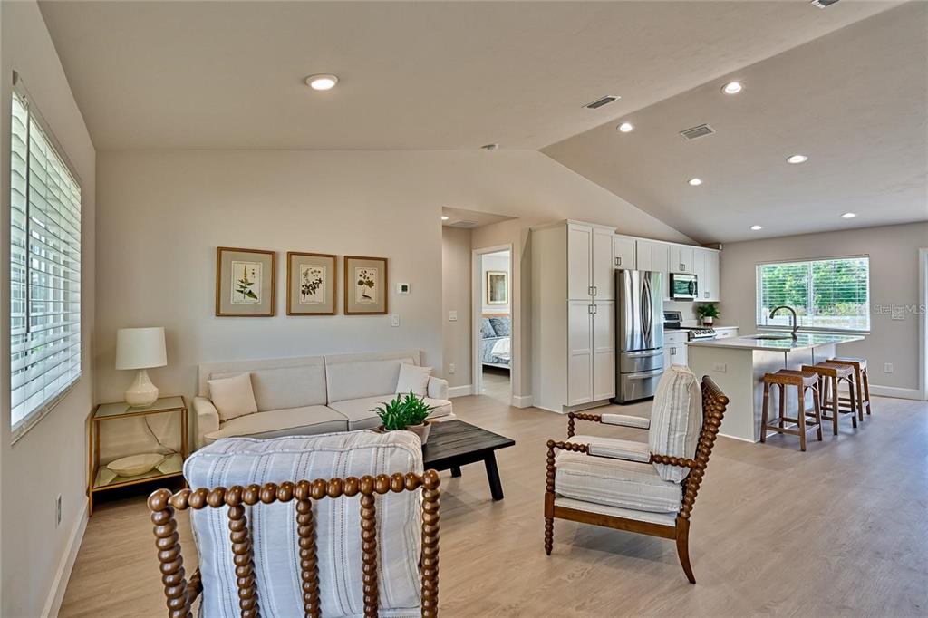An open-concept living room and kitchen featuring light wood flooring and white cabinetry — 135 HARTFORD STREET, HAWTHORNE, FL