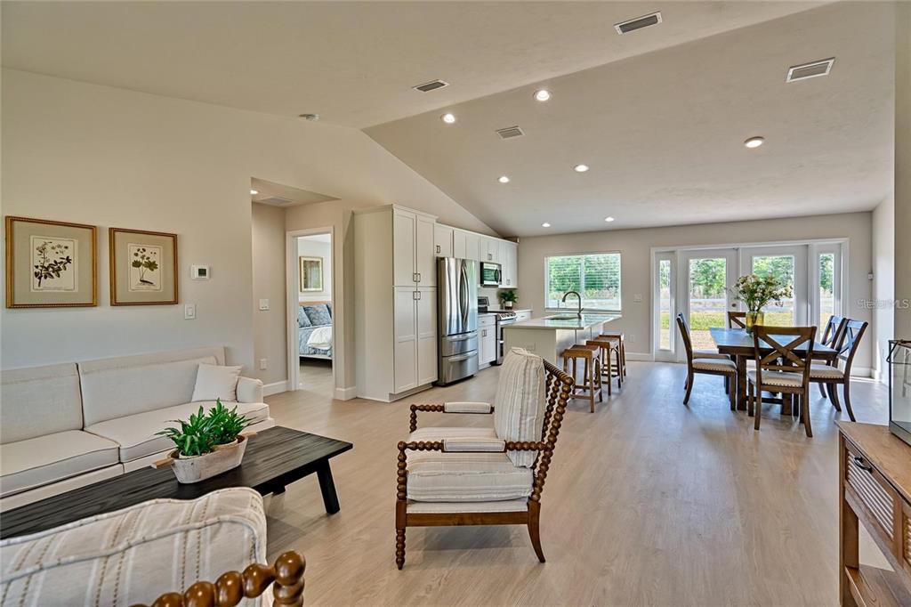 An open-concept living room and kitchen feature light wood flooring and vaulted ceilings — 135 HARTFORD STREET, HAWTHORNE, FL