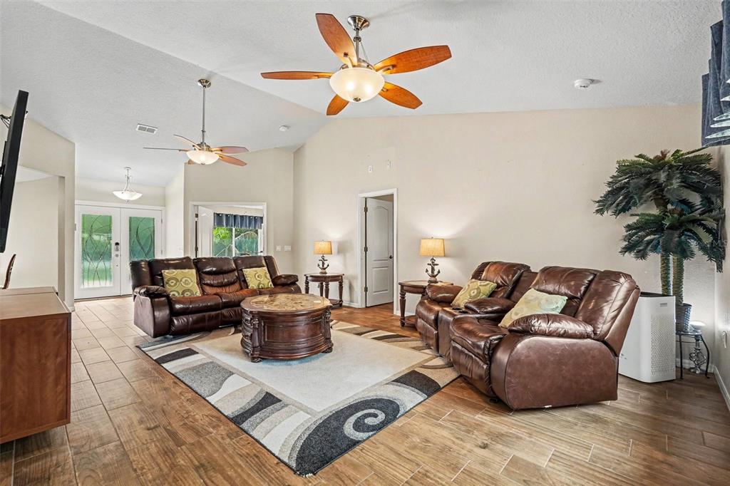 A living room features brown leather furniture, a patterned area rug, and two ceiling fans — 6350 BILTMORE AVENUE, WEBSTER, FL