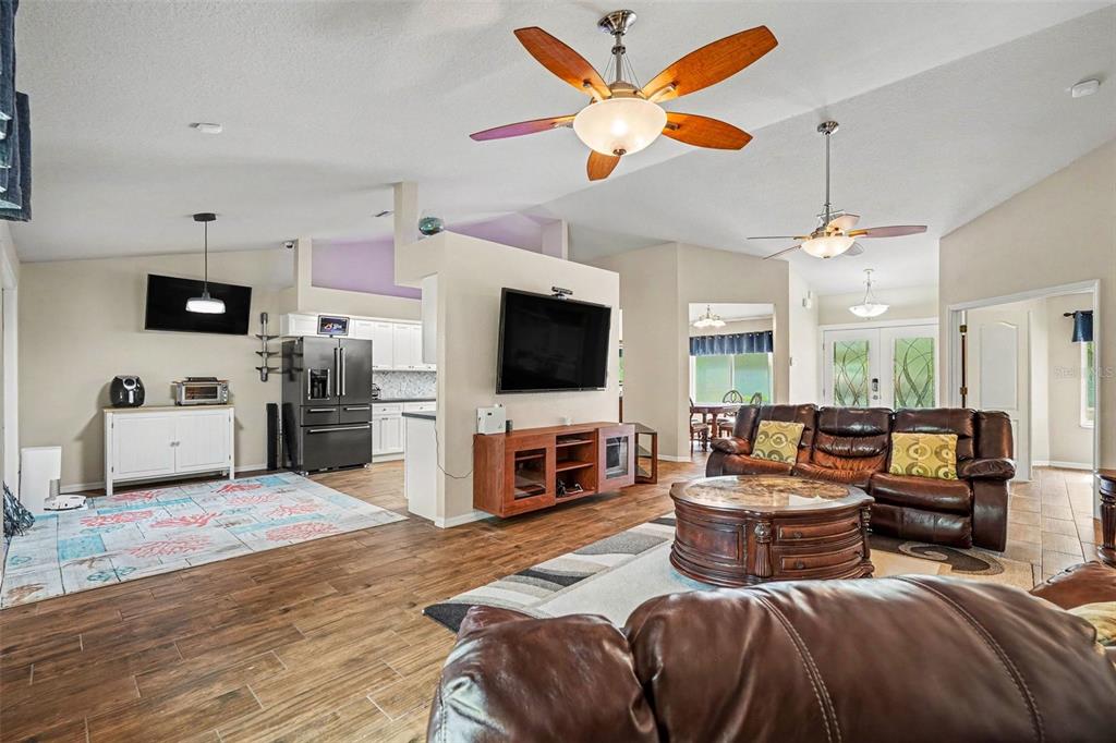 A living room with wood-look tile floors, a ceiling fan, and a wall-mounted television — 6350 BILTMORE AVENUE, WEBSTER, FL