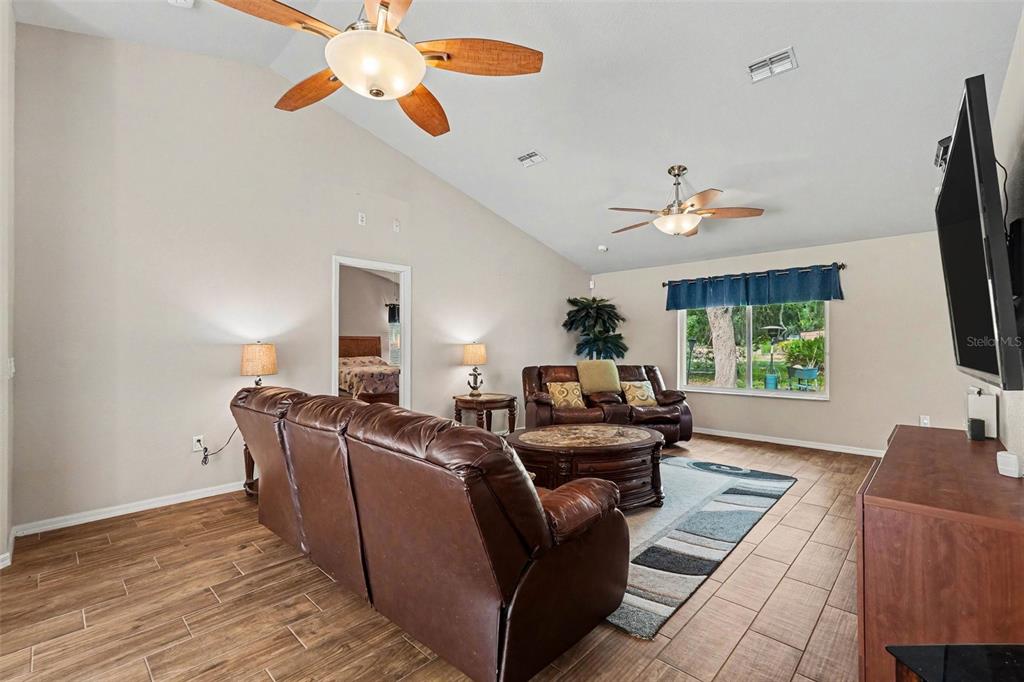 A living room with vaulted ceilings, tile floors, two leather sofas, and two ceiling fans — 6350 BILTMORE AVENUE, WEBSTER, FL