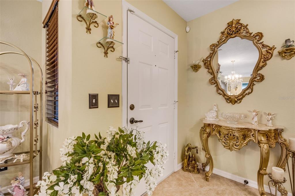 An entryway features a white door, a gold ornate mirror, and a matching console table — 551 GRAND CAYMAN CIRCLE, LAKELAND, FL