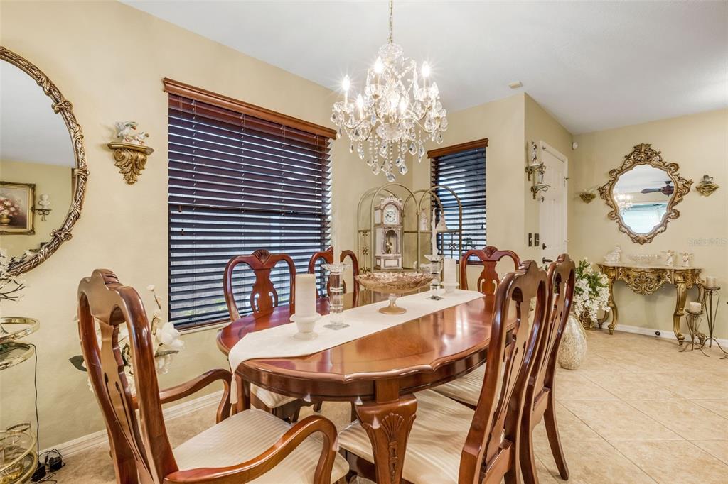 A formal dining room features a wooden table, chairs, a crystal chandelier, and ornate mirrors — 551 GRAND CAYMAN CIRCLE, LAKELAND, FL