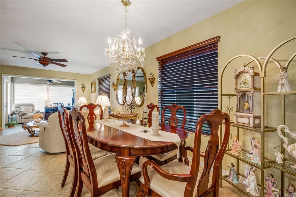 A dining room features a wooden table, chandelier, and a gold display shelf with figurines — 551 GRAND CAYMAN CIRCLE, LAKELAND, FL