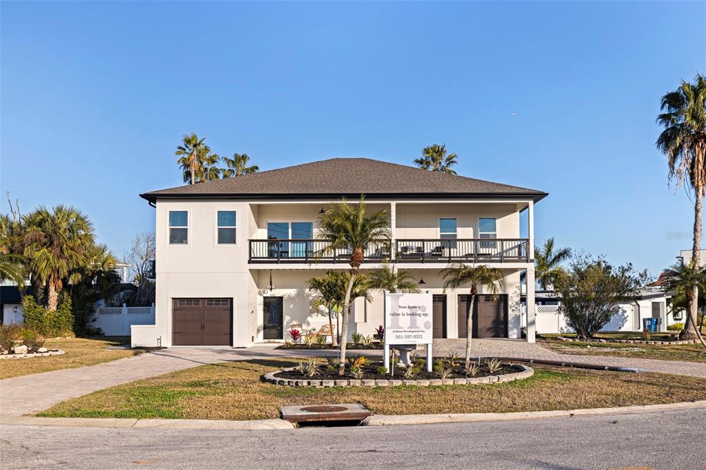 A two-story house with a balcony, two garage doors, and a front yard with palms — 605 115TH AVENUE, TREASURE ISLAND, FL